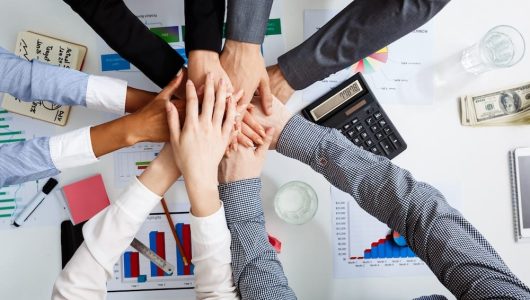 Picture of businessmen's hands on white table with documents, coffee and drafts